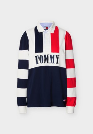Rugby tričko s dlhým rukávom s červenými, bielymi a námorníckymi modrými pruhmi, bielym golierom a textom "TOMMY" cez hruď.