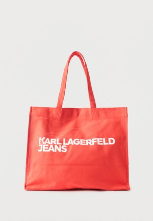 Czerwona materiałowa torba na ramię z długimi uchwytami, z białym, pogrubionym napisem "KARL LAGERFELD JEANS" z przodu na jednolitym tle.