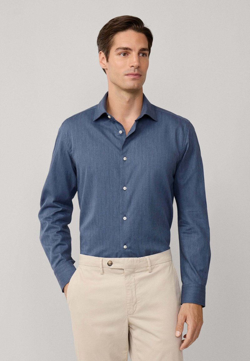 Blauw overhemd met lange mouwen en een button-down kraag, gemaakt van textuurstof, met witte knopen en gecombineerd met lichtbeige broeken.