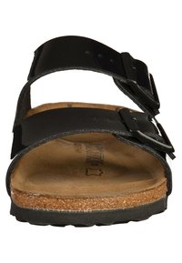 Svart sandal med två remmar och justerbara spännen, korkfotbädd, strukturerad gummiyttersula och slät ovansida.