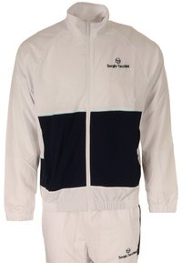 Witte trainingsjack met marineblauwe streep, rits aan de voorkant, en logo op de borst; gemaakt van lichtgewicht stof; elastische manchetten en tailleband voor een goede pasvorm.