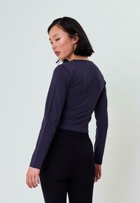 Langsleeve, marineblauw shirt van zachte stof, met een ronde halslijn en een cropped ontwerp. Heeft aansluitende mouwen en een minimalistische uitstraling.