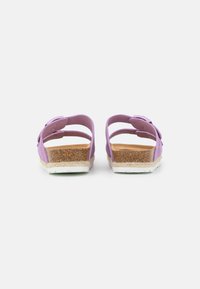 Purple sandals with two wide straps, cork footbed, and textured white sole. Adjustable metal buckle detail. Back view.