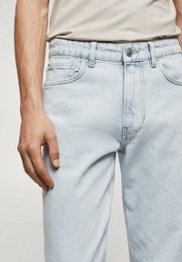 Světle modré džíny z denimu s klasickým pětipocket designem, zapínáním na knoflík a jemným vyblednutím. Tkanina má měkký, strukturovaný povrch.