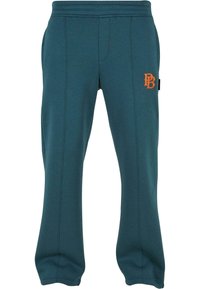 Pantalones de chándal en teal con logo naranja, hechos de una tela suave. Cuentan con bolsillos laterales, cintura elástica y detalles de costura texturizada.