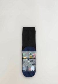 Černé ponožky s barevným městským designem na noze, který zobrazuje budovy, stromy a silnici, tisknuté na šedém pozadí. Směs bavlny.
