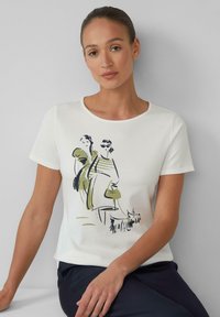 Wit katoenen t-shirt met korte mouwen, voorzien van een bedrukte afbeelding van twee vrouwen en een hond in groen en zwart. Ronde halslijn, casual pasvorm.