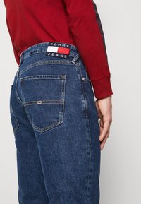 Denimjeans i mörkblått med rak passform. Har en sydd logotyp patch på baksidan av midjan och två bakfickor med minimala detaljer.