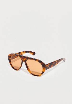 Tortoiseshell patterned sunglasses with amber-tinted lenses and thick rectangular frames displayed on a light background.