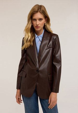 Blazer en cuir marron foncé avec une coupe ajustée, fermeture à un bouton, deux poches avant et revers crantés, associé à une chemise bleu clair.