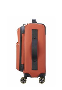 Valigia rigida di colore arancione con una superficie liscia, accenti neri, maniglia laterale, grande zip e quattro ruote con bordatura gialla per una maggiore mobilità.