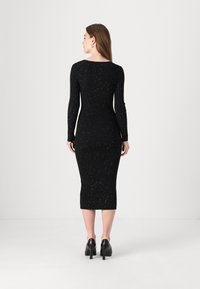 Black ribbed knit dress with long sleeves, knee-length hem, and silver speck accents, featuring a fitted silhouette and scoop back design.