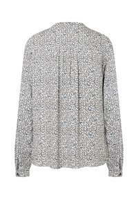 Weiße Bluse mit langen Ärmeln, verziert mit einem schwarzen und blauen Herzmuster, mit plissiertem Rückenteil und mit Knöpfen versehene Manschetten als Detail.