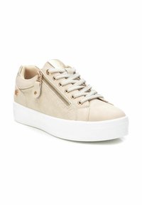 Sneaker beige con un design trapuntato testurizzato, con accenti metallici e una cerniera laterale. La suola platform bianca e i lacci argentati completano il look.