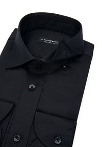 Czarna koszula męska z gładkiego materiału, z kołnierzykiem typu pointed, zapinana na guziki z przodu oraz z dwiema kieszeniami na piersi z czarnymi guzikami.