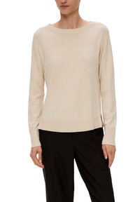 Helle beige Langarmpullover mit weitem Rundhalsausschnitt, gerippten Bündchen und Saum, seitlichen Schlitzen und einer glatten Textur. Kombiniert mit schwarzen Hosen.