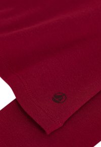 Tessuto in fibra rossa con una superficie liscia, caratterizzato da un logo nero nell'angolo e cuciture ordinate lungo i bordi.