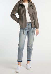 Grå hættetrøje med snoretræk, frontlommer, parret med lys blå slidte jeans og hvide sneakers. Glat stofoverflade.
