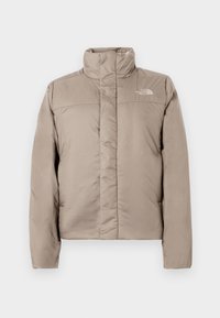 Geacă puffer de culoare bej deschis, cu guler înalt, design matlasat și logo în partea stângă sus a pieptului. Textură netedă și închidere cu fermoar în față.