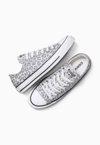 Zapatillas de lona con estampado de leopardo gris y blanco, suelas de goma blanca, diseño clásico con cordones y acentos negros a lo largo de la base.