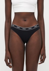 Zwarte slip met een witte merkband. Gemaakt van zacht materiaal, met een minimalistisch ontwerp en een lage taille.