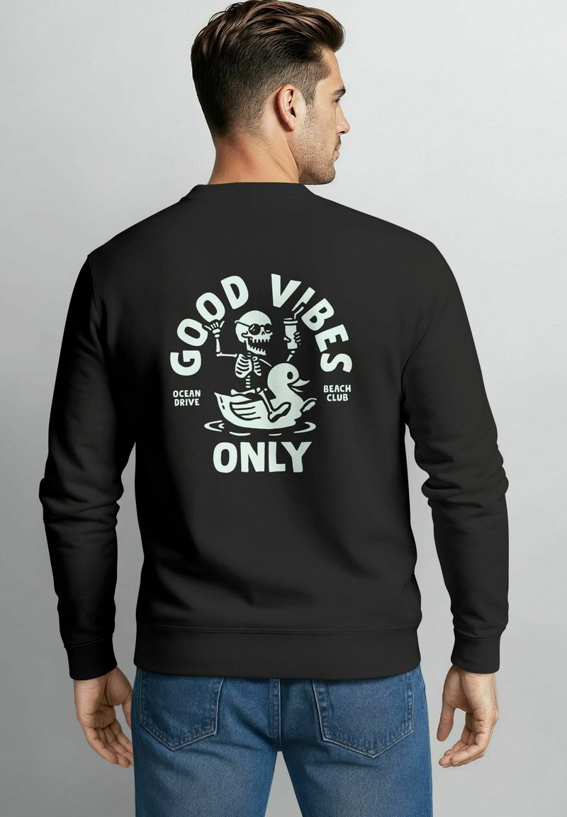 Schwarzer Sweatshirt mit Grafik auf der Rückseite, die ein Skelett und eine Ente zeigt, Text mit der Aufschrift "NUR GUTE VIBES", lässige Passform mit langen Ärmeln.