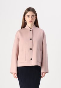 Kurzer, pinkfarbener Wollmantel mit hohem Kragen, vorderer Knopfleiste und zwei großen Taschen. Besitzt lässige Ärmel und ein sauberes, modernes Design.