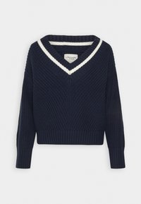 Granatowy sweter z dzianiny z głębokim dekoltem w kształcie litery V i kontrastującymi białymi paskami. Posiada prążkowane mankiety i dół, teksturowany materiał oraz luźny krój.