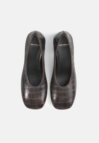 Balerini din piele ecologică maro, cu textură de crocodil, vârf rotund și interior negru neted. Detaliate cu accente subtile de cusătură.