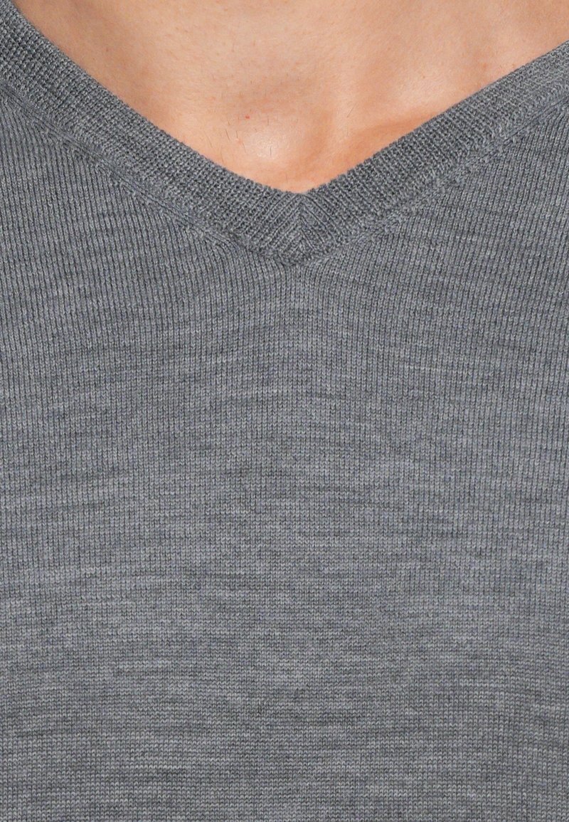 Grijze V-hals gebreide trui met een ribbelstructuur. De stof is zacht en lichtgewicht, met gelijkmatige stiksels en subtiele kleurvariaties.