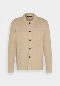 Cárdigan de punto beige con cierre de botones al frente, cuello y un bolsillo en el pecho. Presenta una tela texturada y botones marrones.