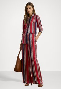 Striped red, navy, and white blouse with button-down collar, paired with matching wide-leg pants. Smooth fabric and elastic waist detail.