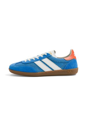Baskets basses bleues avec des bandes blanches, une semelle en caoutchouc marron, des lacets blancs et un onglet de talon orange avec des inscriptions blanches.