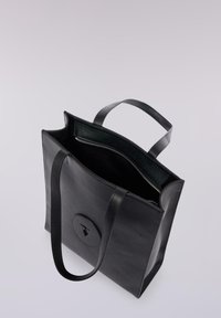 Svart läderhandväska med två handtag, minimalistisk design, med en cirkulär logotyp, innerficka med dragkedja och slät yta.