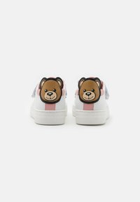 Zapatillas blancas con suela gruesa, con detalles en rosa y un diseño de cara de oso en el talón. Cintas de tela suaves complementan el diseño.