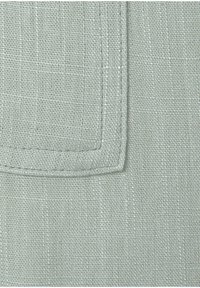 Light gray linen fabric featuring a textured weave with a faint grid pattern and a stitched hem along the edge. Soft texture visible.