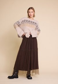Avslappet passform, kremfarget mohair-sweater med mønstret bærestykke; lagdelt brun tyll maxiskjørt; svarte hæler med klogg; belte med stoffrose aksent.