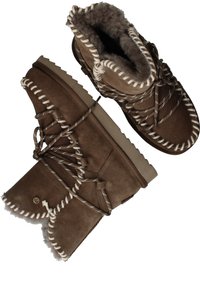 Bruine suède enkellaarsjes met witte stiksels, een getextureerde faux bontvoering en kruislings gespen. Rubberen zolen bieden grip. Kenmerkende golvende bovenrand.