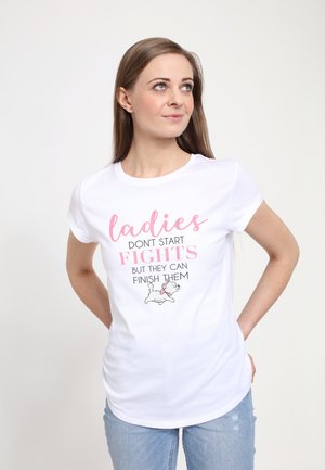 T-shirt en coton blanc avec du texte rose et noir : "les filles NE COMMENCENT PAS LES BAGARRES MAIS ELLES PEUVENT LES TERMINER", accompagnée d'une illustration d'un chat.