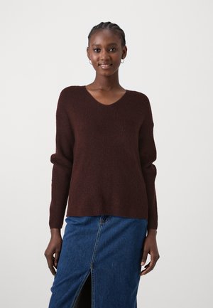 Pull en tricot bordeaux avec un col en V, des manches longues et une coupe décontractée, associé à une jupe en denim avec une fente à l'avant.
