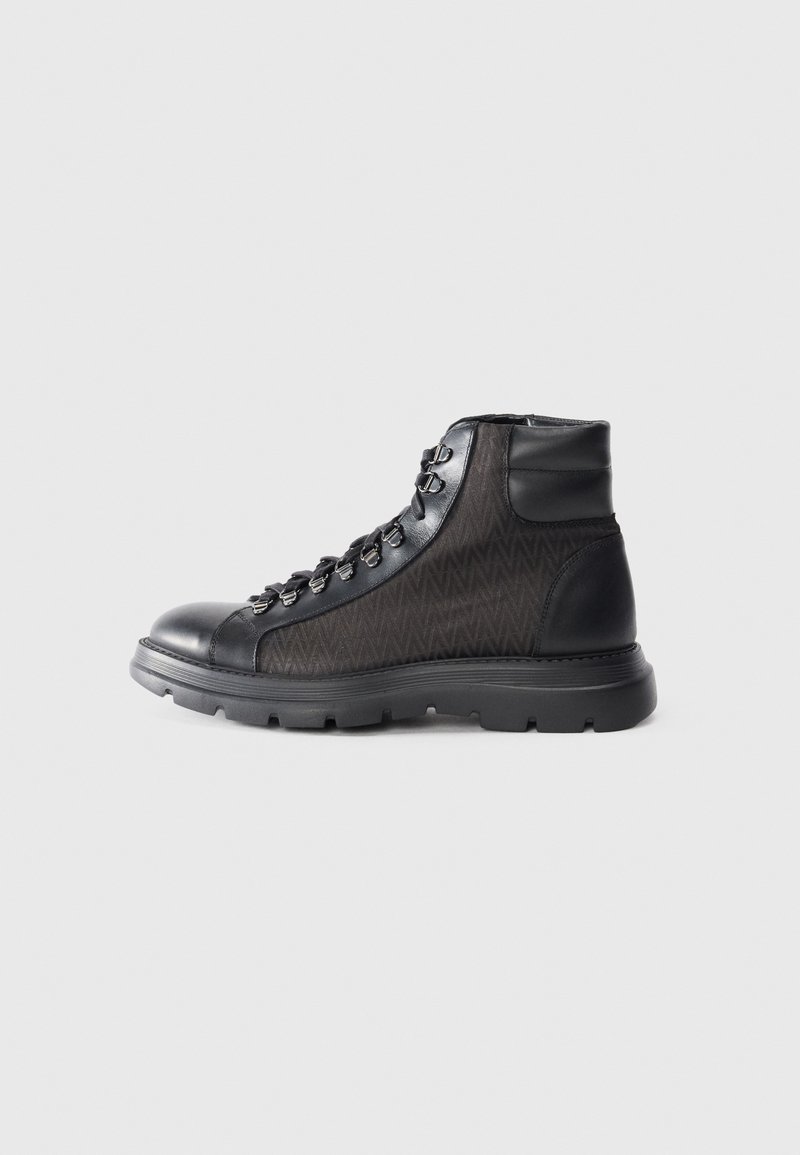 Stivale da trekking nero con un corpo in tessuto nero texturizzato, punta arrotondata, design con lacci e una spessa suola in gomma per la trazione.