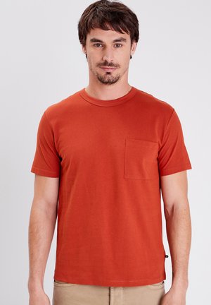 T-shirt in cotone rosso con scollo rotondo, maniche corte e taschino sul lato sinistro del petto. Tessuto liscio con dettagli di cucitura leggeri.
