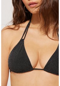 Černý trojúhelníkový bikiny top s třpytivou texturou, má tenké ramínka a minimální pokrytí. Materiál vypadá měkce a pružně.