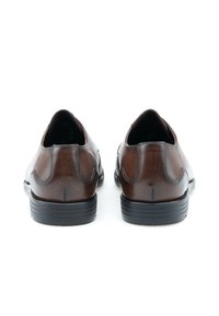 Scarpe in pelle marrone con finitura lucida, punta tonda e suola in gomma nera a contrasto. Presentano cuciture sottili e una superficie liscia.