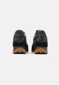 Paire de baskets noires décontractées avec semelles en gomme vues de dos, arborant le logo « Pepe Jeans London » sur les colliers de talon.
