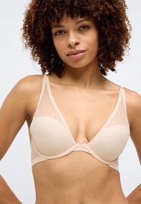 Nude trokutasti grudnjak s glatkom podstavom, prozirnim čašama, širokim naramenicama i dekorativnim detaljem u sredini.