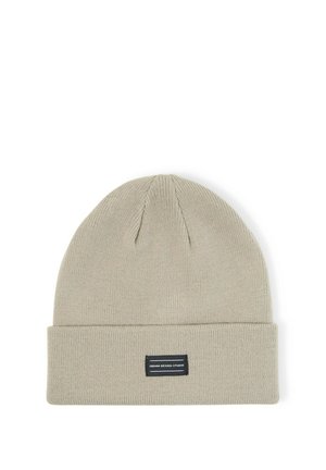Light beige knit beanie with folded brim and small rectangular black label reading Denim Design Studio centered on front.
