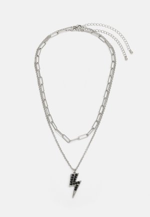 Srebrny naszyjnik warstwowy z łańcuchem w kształcie spinacza i zawieszką w kształcie błyskawicy z czarnymi akcentami. Regulowany zapięcie i długość łańcucha.