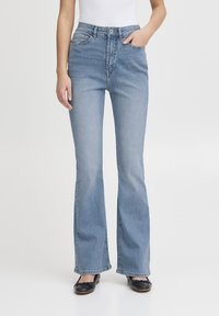 Jeans a zampa d'elefante blu con vita alta, dotati di tasche frontali e chiusura con bottone. Realizzati in denim con una texture liscia e un lavaggio chiaro.