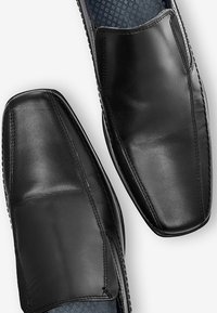 Czarne skórzane eleganckie buty na gładkim wykończeniu, o kwadratowym nosku i subtelnych detalach szycia. Wnętrze wykończone jest wzorzystą podszewką tekstylną.